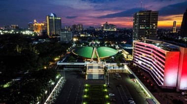 Endonezya Parlamento Kompleksi 'nin hava aracı görüntüsü, aynı zamanda günbatımında gürültü bulutu ile Cakarta şehir manzaralı DPR / MPR binası olarak da bilinir. JAKARTA - Endonezya. 11 Nisan 2021