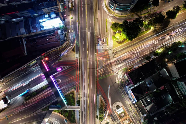 Senen 'deki şehir trafiğinin hava görüntüsü geceleri kesişiyor. Araçlar binalar arasındaki yolda ilerliyor. Jakarta, Endonezya, 28 Nisan 2021