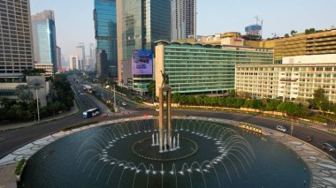 Otel Endonezya Kavşağı 'ndaki şehir trafiğinin hava görüntüsü. Araçlar binalar arasındaki yolda ilerliyor. Jakarta, Endonezya, 13 Mayıs 2021