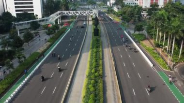 Anayolda, motosiklette ve arabada bisiklet süren bisikletli grubun hava görüntüsü. Dron manzaralı bisiklet kırsal yolda araba yolunda. JAKARTA - Endonezya. 21 Mayıs 2021 