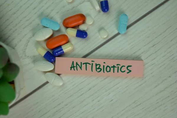 Antibiotics write on sticky notes isolated on Wooden Table.