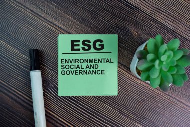ESG - Environmental Social and Governance write on sticky notes isolated on Wooden Table.
