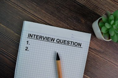 Interview Question write on a book isolated on Wooden Table.