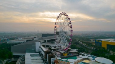 Gün batımında Aydınlatılmış Dönme dolabın hava manzarası, renkli gökyüzü ve dönme dolap. Jakarta, Endonezya, 9 Temmuz 2021