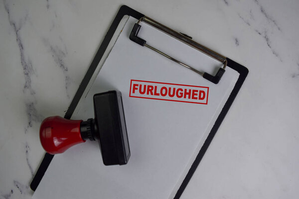 Red Handle Rubber Stamper and Furloughed text isolated on wooden table.