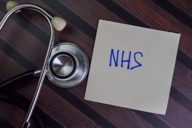 Tahta Masa 'da izole edilmiş yapışkan notlar üzerine NHS yaz.