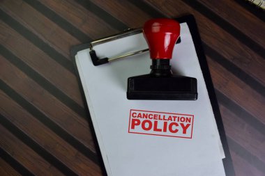 Kırmızı Saplı Lastik Damgalayıcı ve İptal Politikası metni ahşap masada izole edildi.