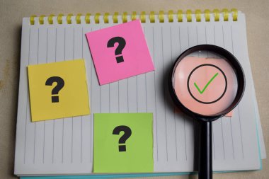 Tahta Masa 'ya izole edilmiş yapışkan notlara doğru ya da doğru ve soru işareti kavramı, soruşturmayı, doğruluğu ya da gerçeği simgeler..