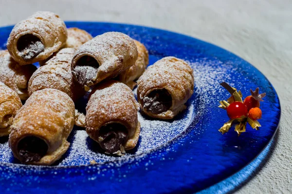 Chocolate cannoli. Italian chocolate sweets on blue plate and white background.