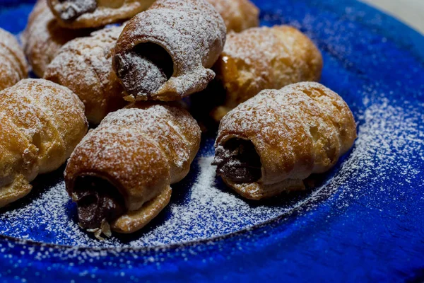 Chocolate cannoli. Italian chocolate sweets on blue plate and white background.