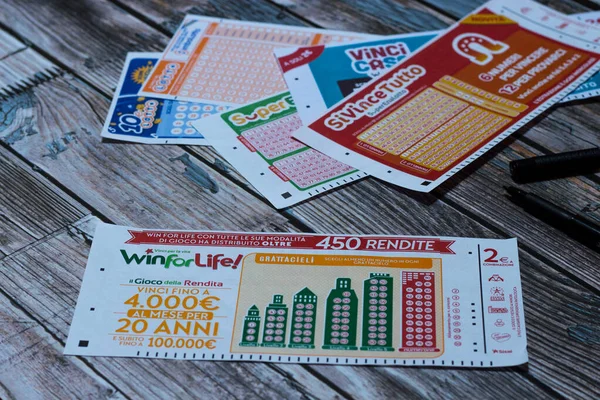 Ön planda hayat kuponu ve arka planda diğer Superenalotto kuponlarını kazan. Seçici odaklanma. Ahşap arkaplan