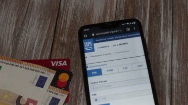 INPS web sitesinin akıllı telefon ekranında, arkaplanda ve banka kartlarında açılması.