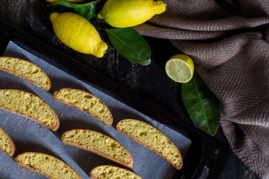 Ev yapımı limonlu kurabiye. Limonlu ve yapraklı siyah ahşap zemin.