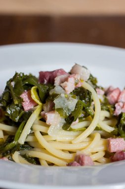 Eski ahşap arka planda roka ve pastırmalı spagetti, seçici odaklanma..