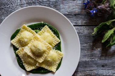 Patates ve havuçla doldurulmuş Ravioli. Borage püresinin üzerinde. Parmesan peyniri ve karabiber serpiştirilmiş.