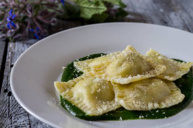 Patates ve havuçla doldurulmuş Ravioli. Borage püresinin üzerinde. Parmesan peyniri ve karabiber serpiştirilmiş.