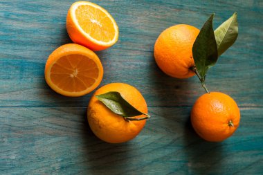 Turuncu kesim ve diğer portakallar morötesi renkli ahşap arka planda.