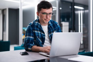 İnternette odaklanmış genç iş adamı çalışması dizüstü bilgisayarda web yayını izliyor eğitim dersi konferansını dinliyor notlar alıyor çalışma masasında oturuyor ve konsept öğreniyor.