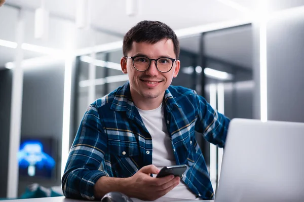 Retrato de belo jovem trabalhando remotamente em casa e sorrindo alegremente para a câmera Fotos De Bancos De Imagens