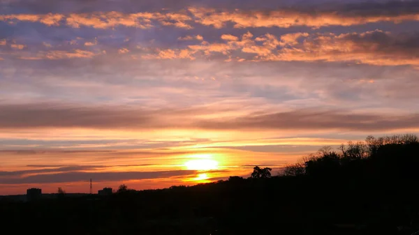 Amazing sunrise in rural scene. Dramatic sky with sunbeam and stratus clouds over the silhouette of hill on the horizon.