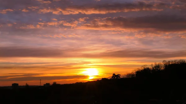 Amazing sunrise in rural scene. Dramatic sky with sunbeam and stratus clouds over the silhouette of hill on the horizon.