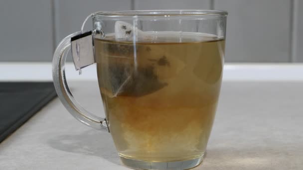 Чайный Мешок Медленно Распространяется Прозрачную Чашку Наполненную Горячей Водой Предыстория — стоковое видео