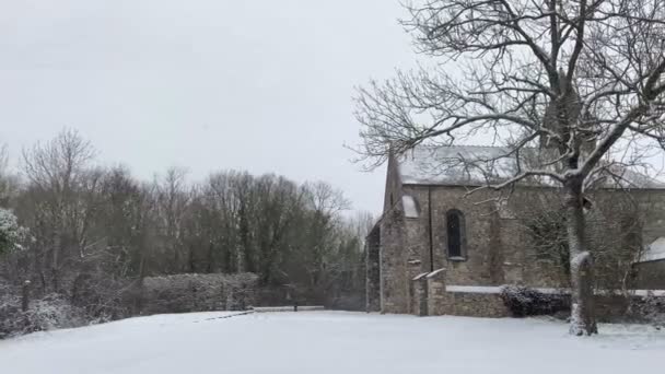 大雪飘落在乡间 背后有一座教堂 镜头前片片的冬季场景 — 图库视频影像