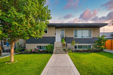 Ön bahçesinde beton yolu olan ortalama bir aile evi.