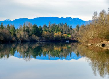 Autumn landscape scene with river, mountains and boat in a quiet factory.
