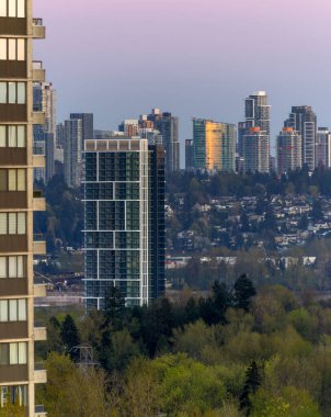 Gün batımında gökyüzü arka planında yüksek binaları olan şehir manzarası Surrey, BC