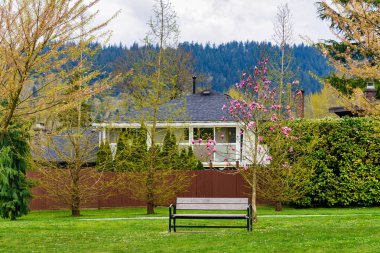 Bulutlu bir bahar gününde, konutların önündeki bankta..