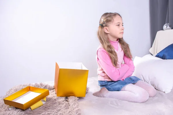 Cute Birthday Girl Opening Boxes Dislike Presents While Sitting Bed Stock Photo