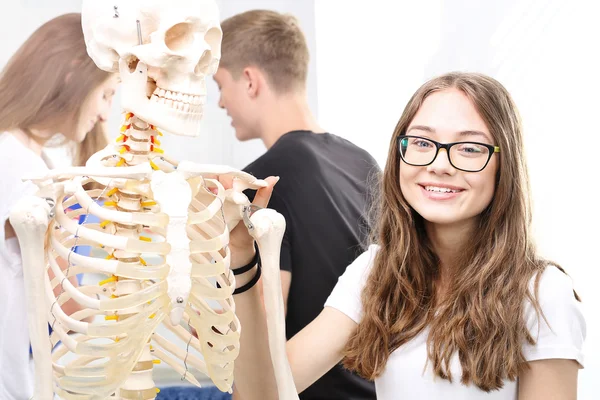 Školačka sleduje model lidské kostry. — Stock fotografie