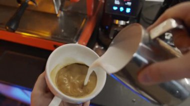 Kapuçino, barmen bardağa köpüklü süt döker. Bir kafede kahve yapmak.