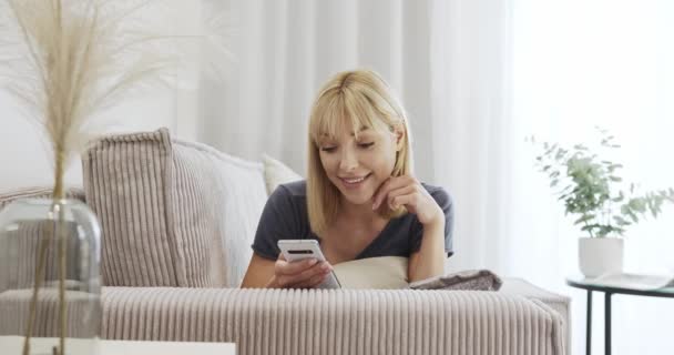 社交媒体在线社交生活 一个小女孩躺在沙发上 用智能手机留言 在沙发上放松 — 图库视频影像