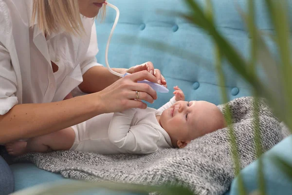 Runny nose in an infant.Mom picks up a runny nose with an aspirator. Baby care.