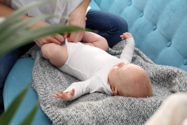 Bebeği giydiriyorum. Anne babası bebeği tişörte koyuyor.