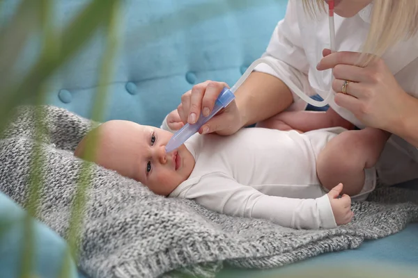 Runny nose in an infant.Mom picks up a runny nose with an aspirator. Baby care.