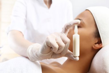 Kozmetik ampül, bir kadın yüze uygulanan serum