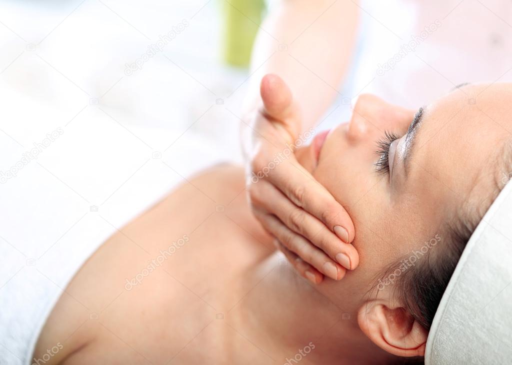 Woman face massage in spa salon