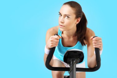 Spinning woman exercising on a stationary bike clipart