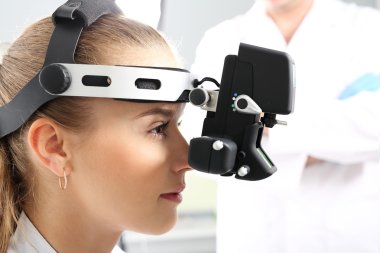 Ophthalmologist examines the eyes using a ophthalmic device clipart