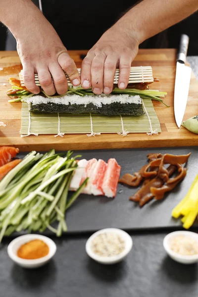 How to prepare sushi. Twisting sushi rolls on a bamboo mat — Stock Photo, Image
