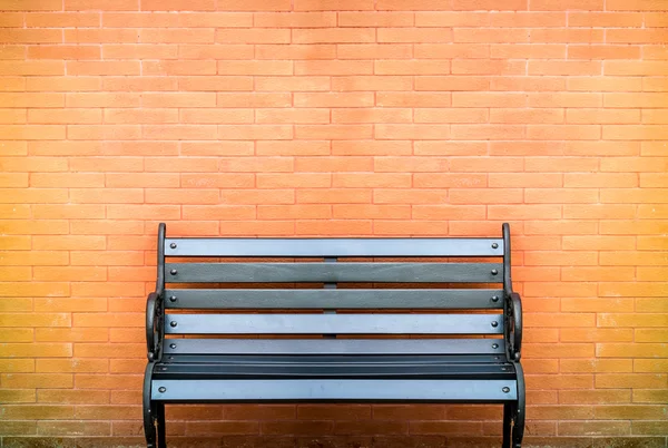 Black bench on brick wall — Stock Photo, Image