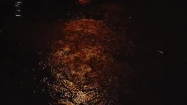 Geceleri yere düşen yağmur damlaları, akan su, akan yağmura yansıyan kırmızı ışık yumuşak bir parıltıyla yansıtıcı desen oluşturur..