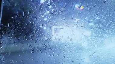 Cama akan yağmur damlaları ve diğer taraftan akan trafik camda gölgeler bırakarak hareket yaratır. Ayar içinde ışık ve su karışımı.