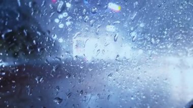 Cama düşen yağmur damlaları ve camda gölgeler bırakan trafik ışıkları, bulanık bir görüntü ve yumuşak bir tonu gösteriyor..