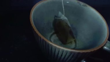 Bardaktaki temiz su siyah çay demlemek için çay poşeti ile doldurulur ve demleme adımlarını gösterir..