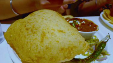 Tabaklar ve kase içinde Bhature ve kolesistektomi olan tabaklar, yanında baharatlı yeşil biber turşusuyla birlikte bir kadının yediği gibi taşınır..