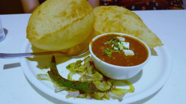 Bir tabak chole bhature peynirle servis edilir ve çeşni ve baharat için biberli turşu..